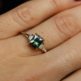 Gold ring with a green gemstone on a person's finger