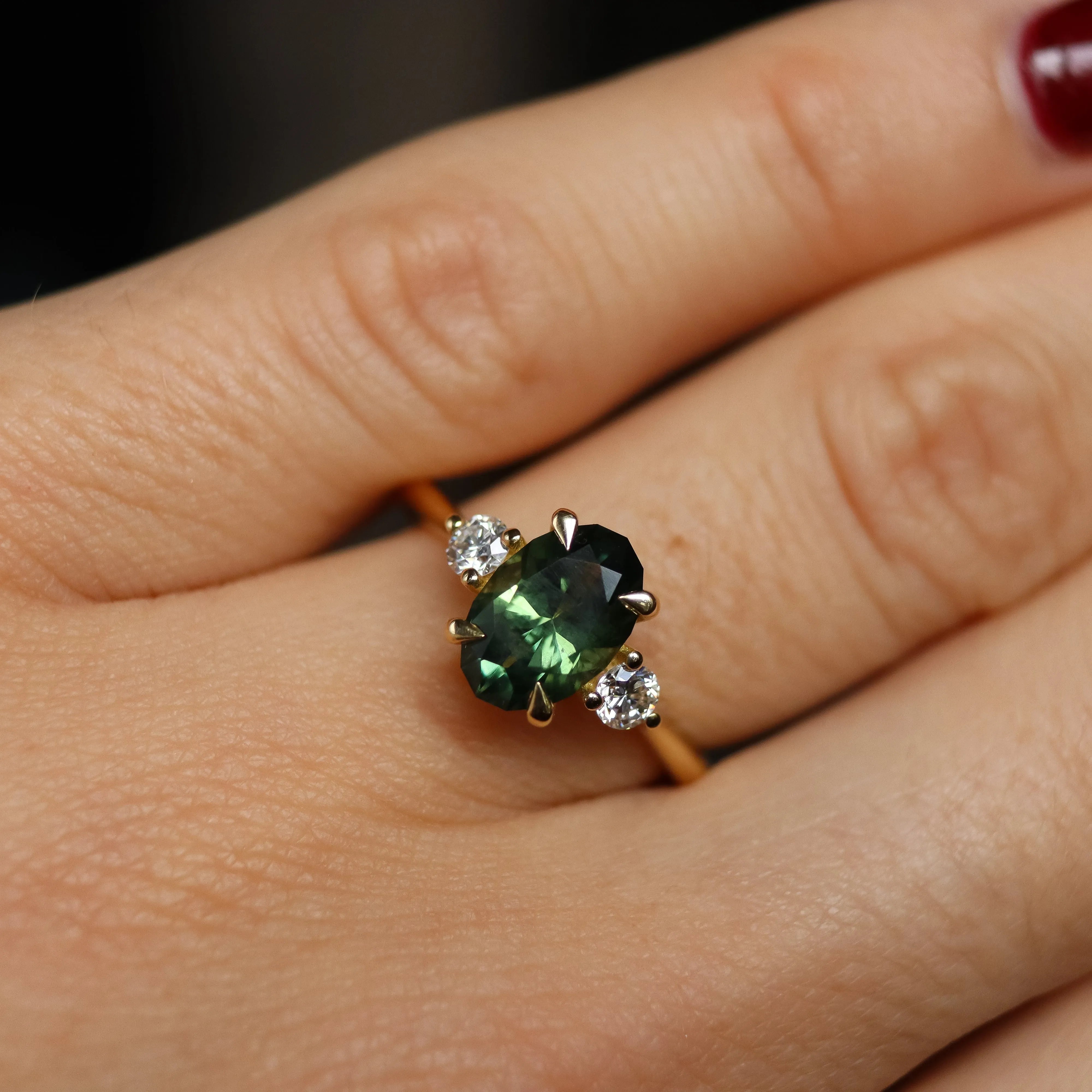 green trilogy engagement ring on hand