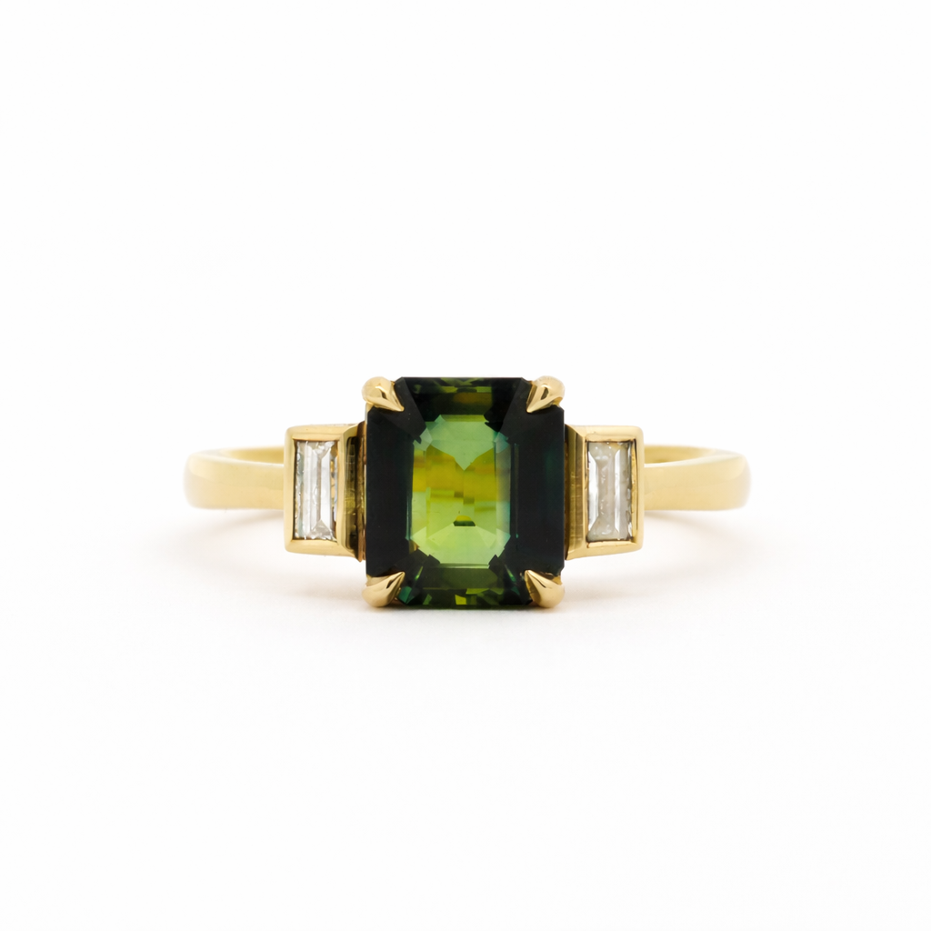Gold ring with a green gemstone and smaller diamonds bezel set on a white background