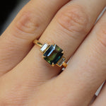 Gold ring with a green gemstone on a hand