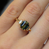 Gold ring with a green gemstone on a hand