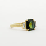Gold ring with a green gemstone on a white background