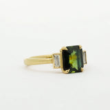 Gold ring with a green gemstone on a white background