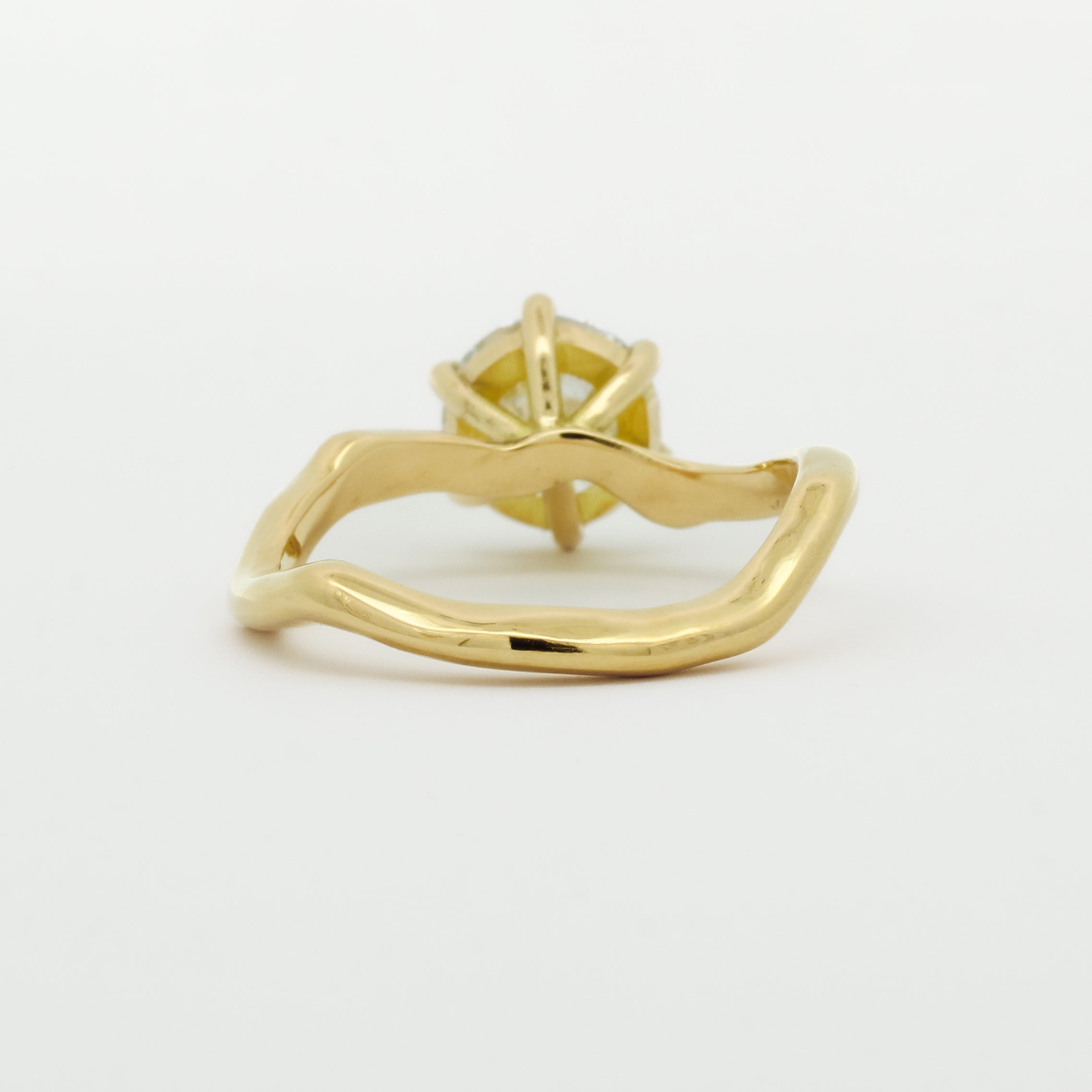 back view of engagement ring with wavy design on a white background