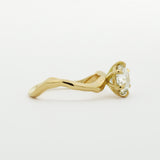 side view of wavy engagement ring with a diamond on a white background