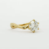 Gold engagement diamond ring with curved band on a white background