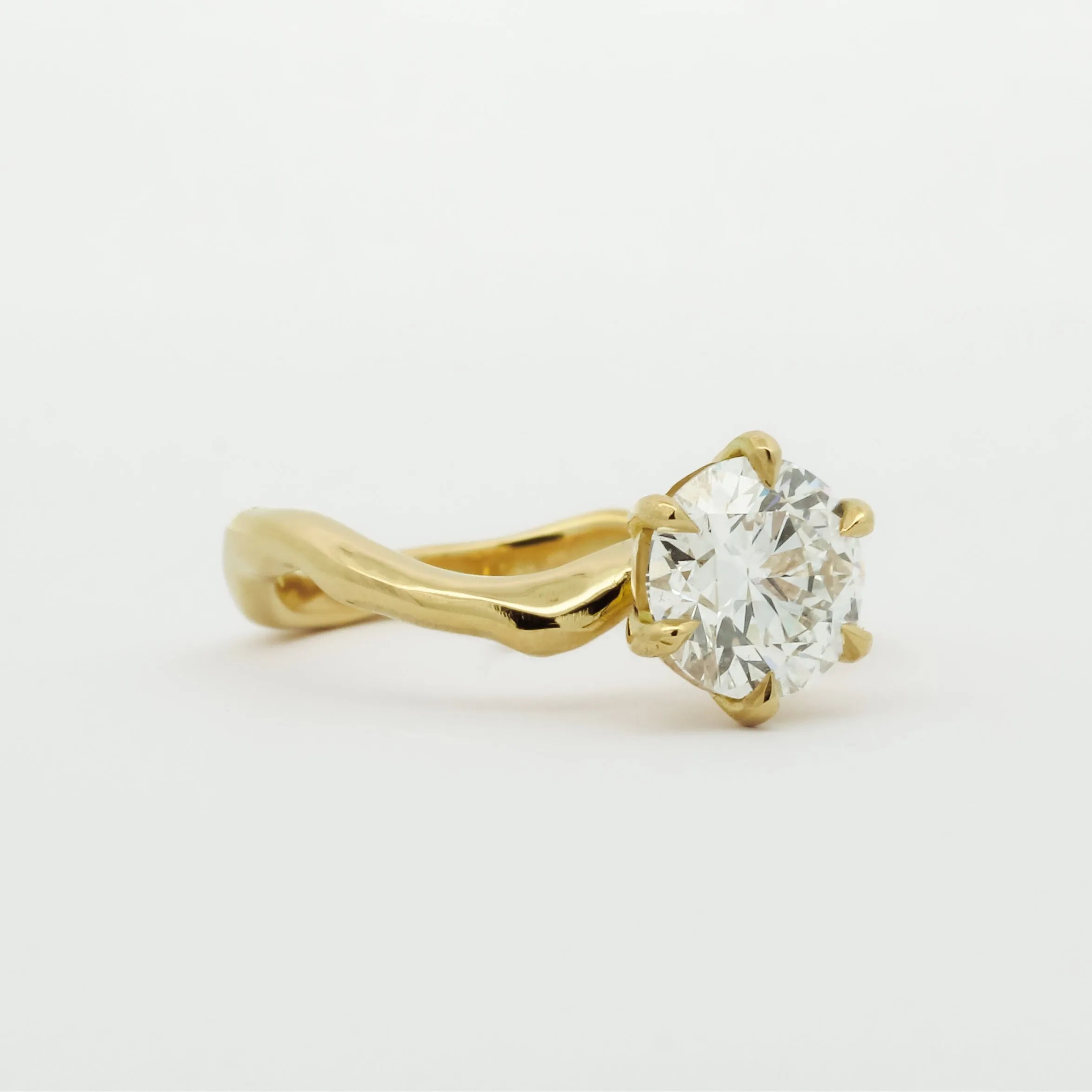 Gold engagement diamond ring with curved band on a white background