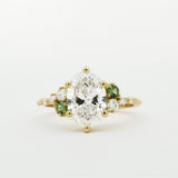 Gold ring with a large diamond and smaller green diamonds on a white background