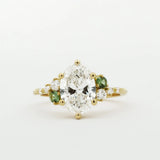 Gold ring with a large diamond and smaller green diamonds on a white background