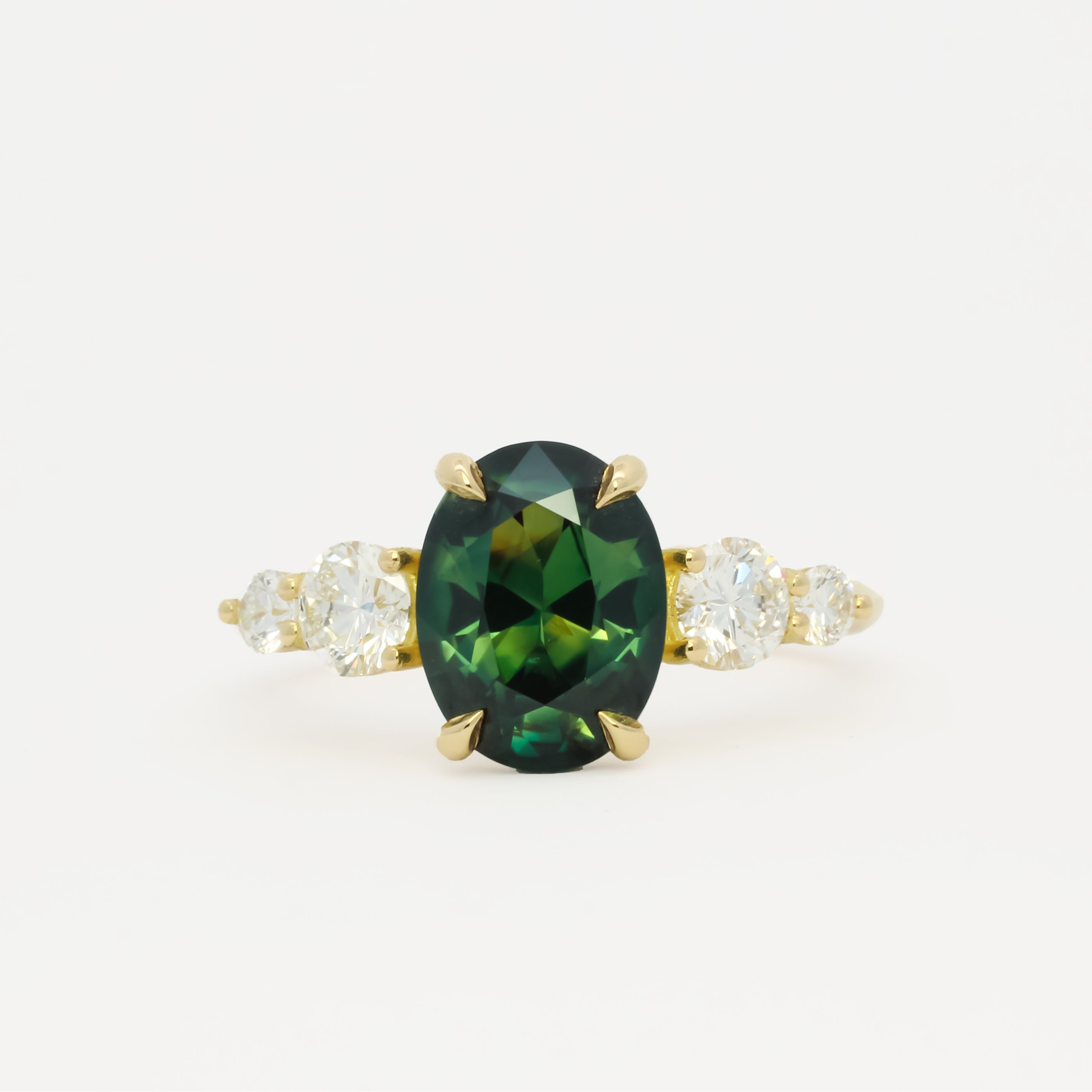 large green sapphire engagement ring with tapered round diamonds on a white background