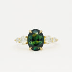 large green sapphire engagement ring with tapered round diamonds on a white background