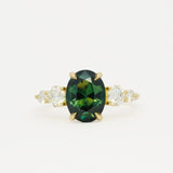 large green sapphire engagement ring with tapered round diamonds on a white background