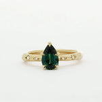 Gold ring with a green pear sapphire and diamonds in star engraving on a white background