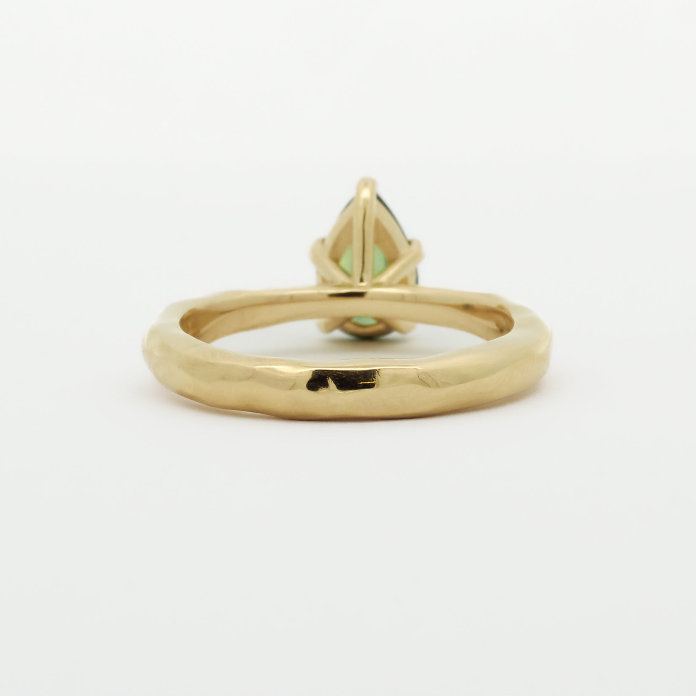 back view of a pear green sapphire engagement ring with textured band