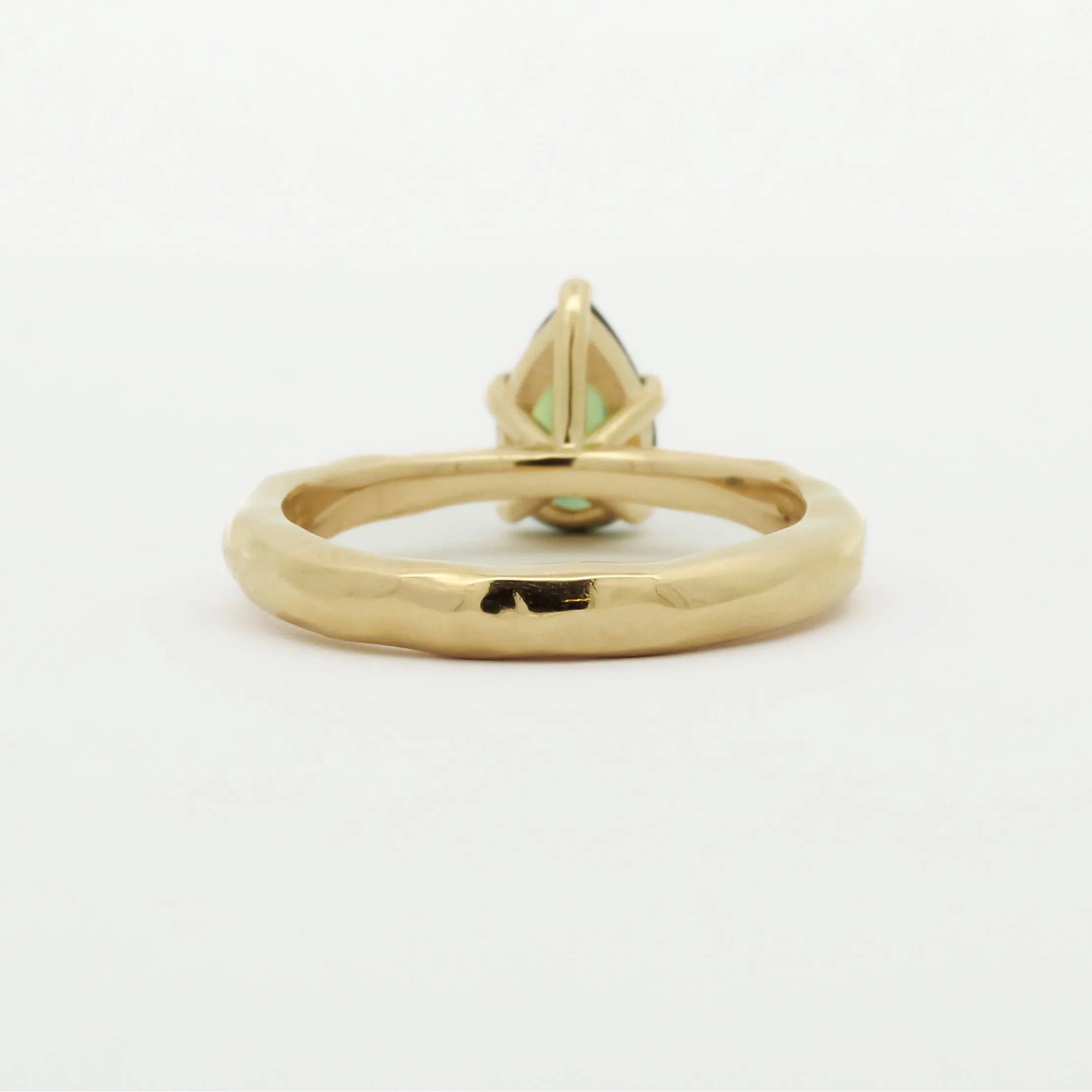 back view of a pear green sapphire engagement ring with textured band