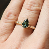 gold engagement ring with pear sapphire and star set diamonds on a hand