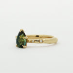 Gold ring with a green gemstone and star-framed diamonds on a white background