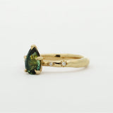 Gold ring with a green gemstone and star-framed diamonds on a white background