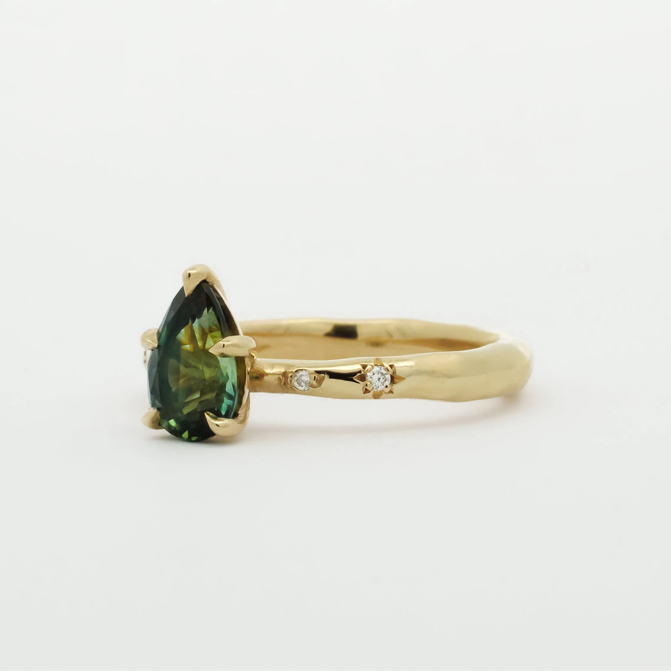 Gold ring with a green gemstone and star-framed diamonds on a white background