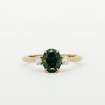 Gold ring with a green and blue gemstone and two smaller diamonds on a white background