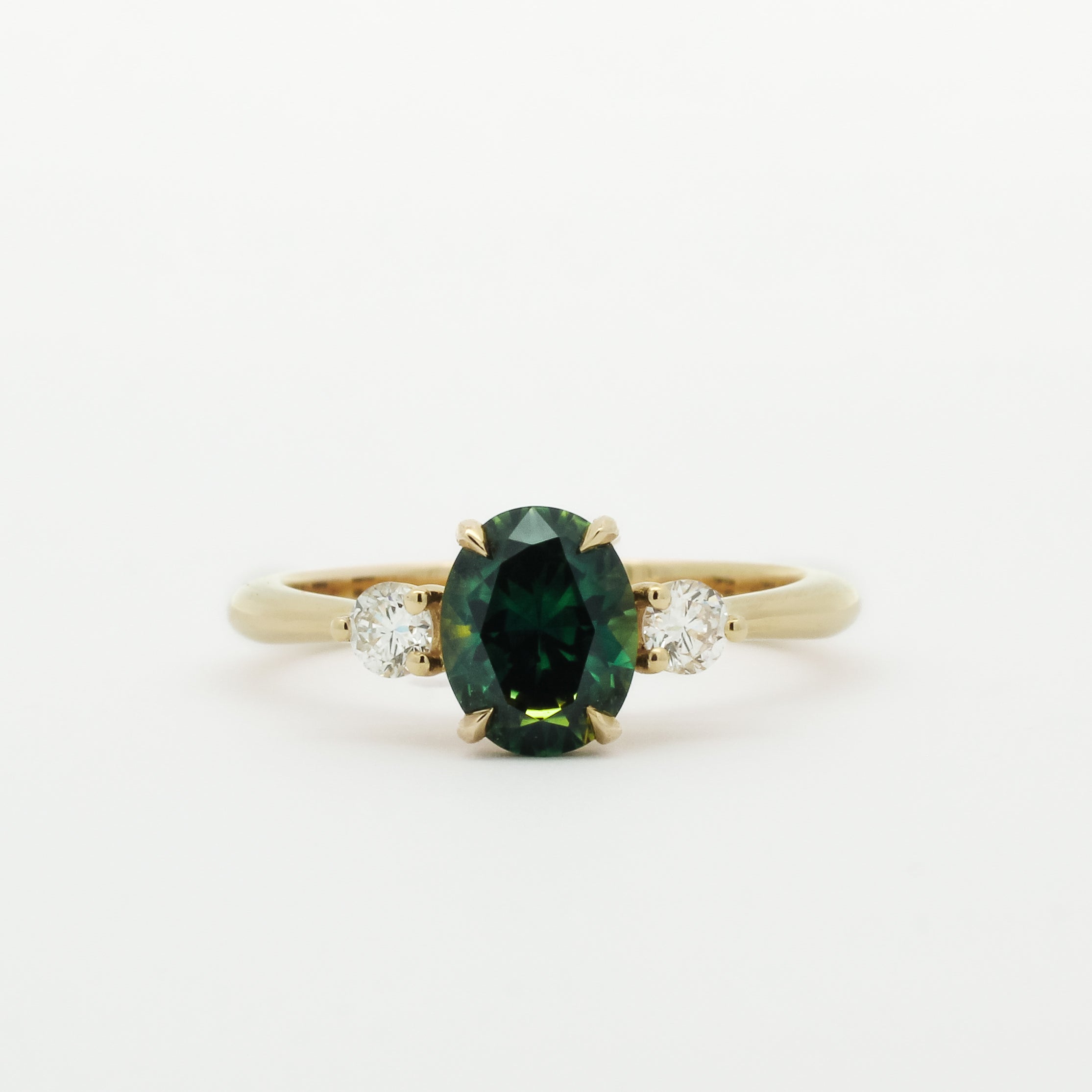 Gold ring with a green and blue gemstone and two smaller diamonds on a white background