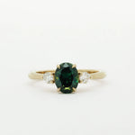 Gold ring with a green and blue gemstone and two smaller diamonds on a white background