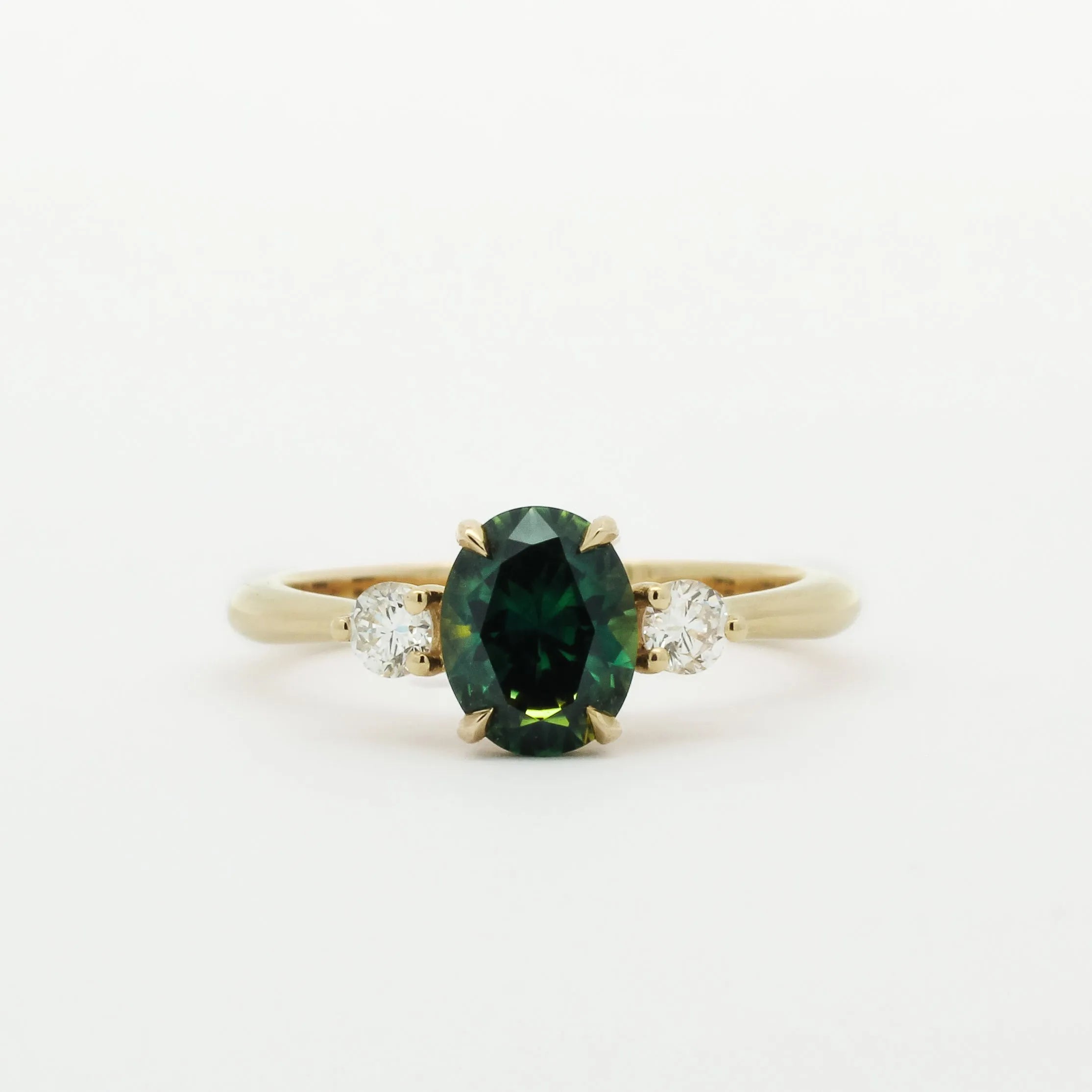 Gold ring with a green and blue gemstone and two smaller diamonds on a white background