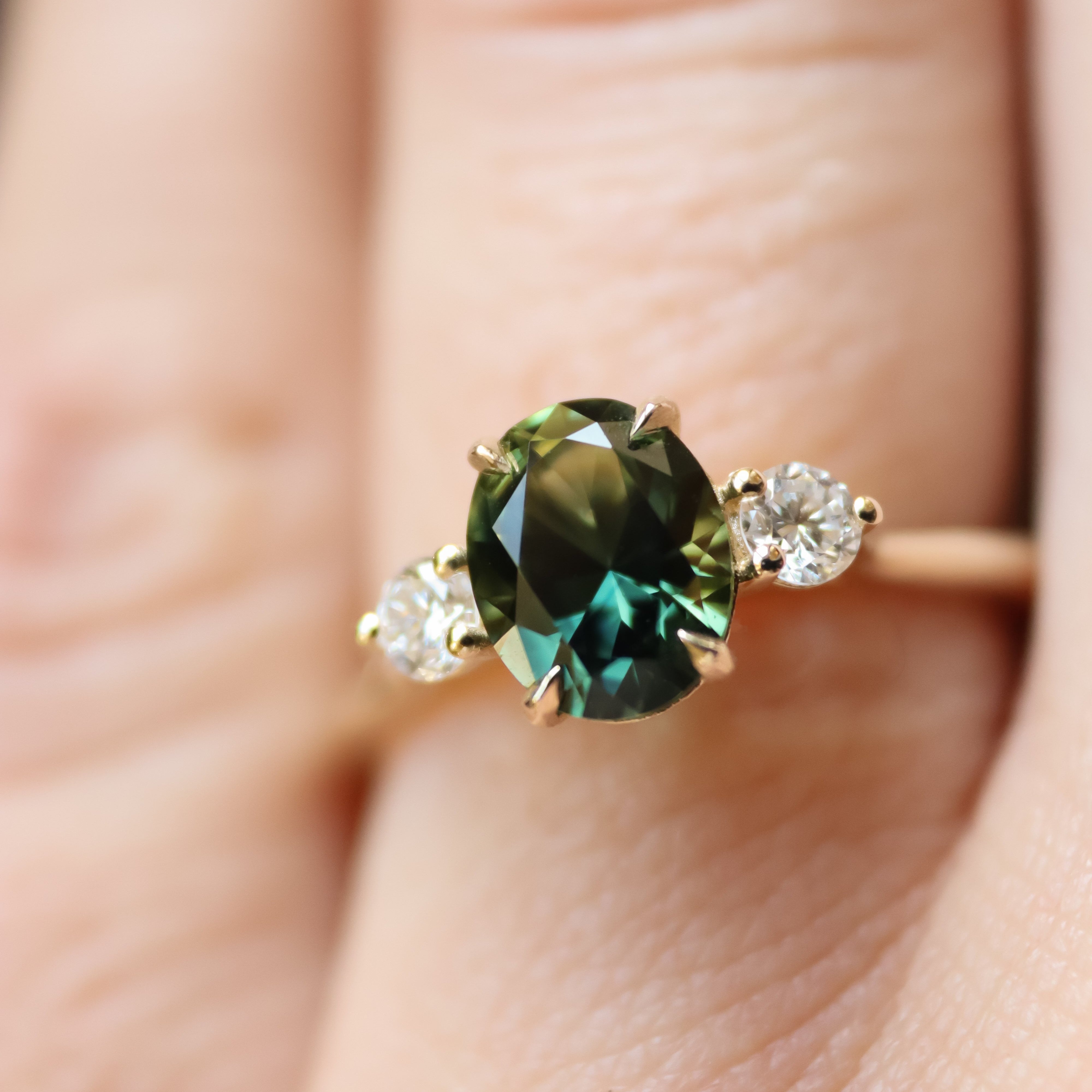 Ring with a green gemstone and smaller diamonds on a finger