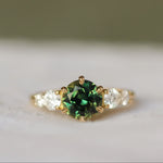 sapphire engagement ring with round parti sapphire and round diamonds set in gold with a blurred background 