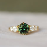 sapphire engagement ring with round parti sapphire and round diamonds set in gold with a blurred background 