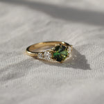 Gold ring with a green gemstone on a light fabric background in the sun