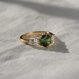 Gold ring with a green gemstone on a light fabric background in the sun