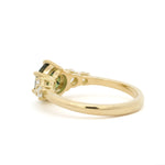 back view of a gold engagement ring with a green gemstone on a white background