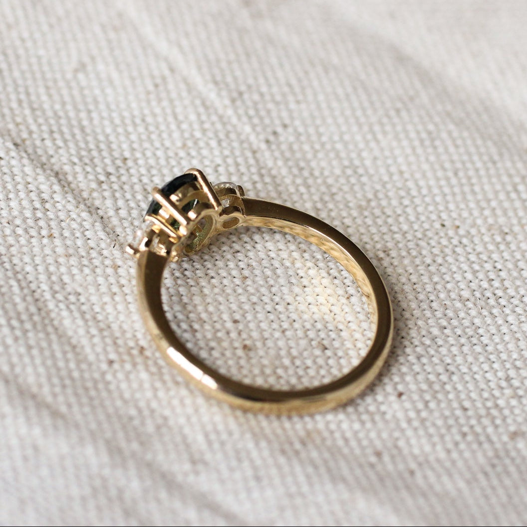 Gold ring with a gemstone and low-set collet on a textured white fabric background
