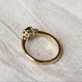 Gold ring with a gemstone and low-set collet on a textured white fabric background