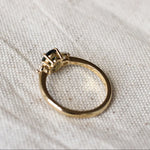 Gold ring with a gemstone and low-set collet on a textured white fabric background