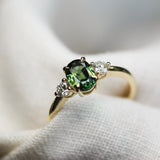 green sapphire low-set engagement ring with 3mm diamonds in white fabric