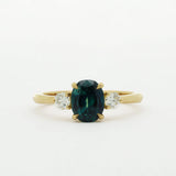 Gold ring with a green gemstone and two smaller diamonds on a white background
