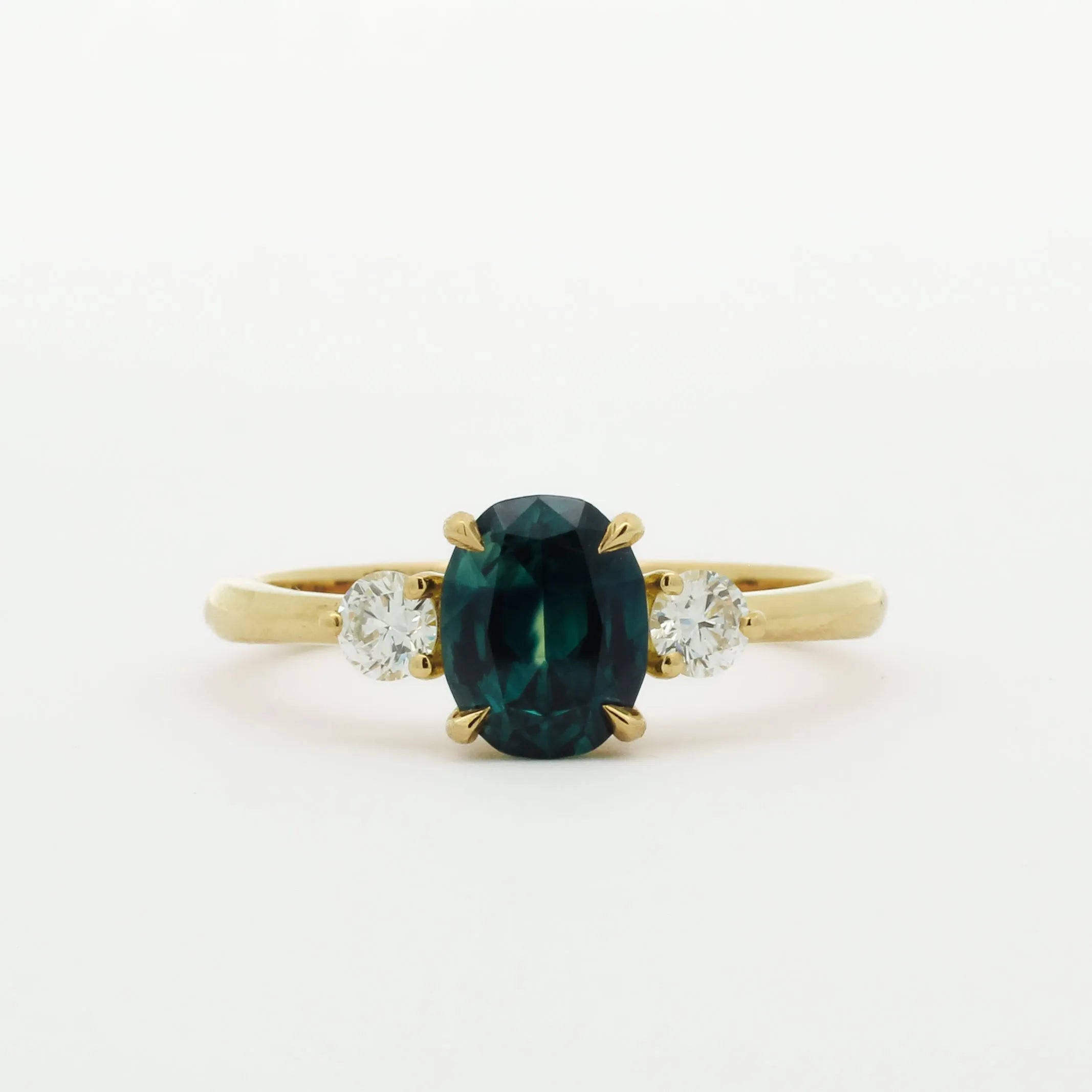 Gold ring with a green gemstone and two smaller diamonds on a white background