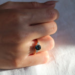 engagement ring with blue oval sapphire and round diamonds worn on hand in sunlight