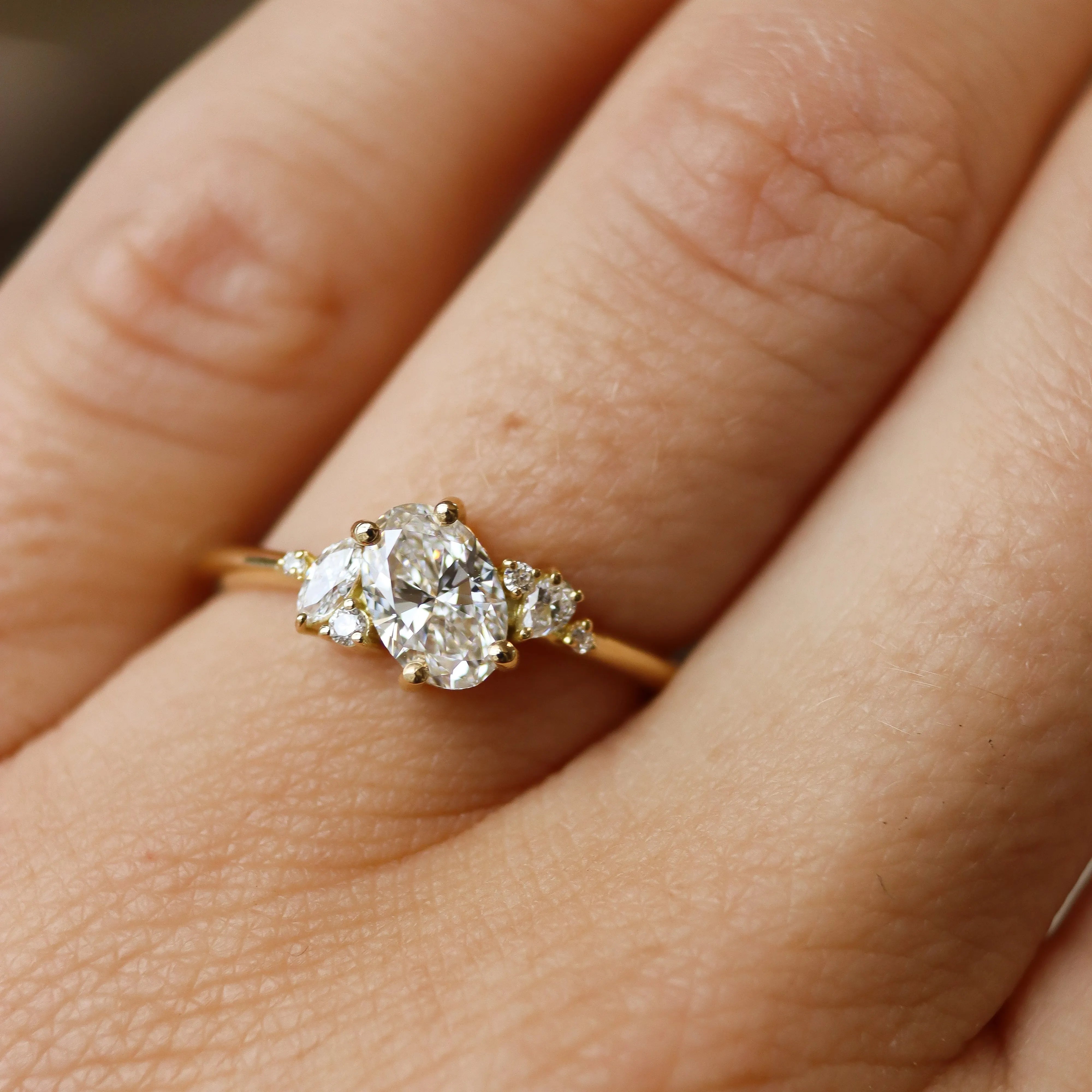 close up of hand wearing a diamond oval and marquise engagement ring