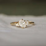 Gold engagement ring with oval, pear and marquise diamonds on a soft fabric background