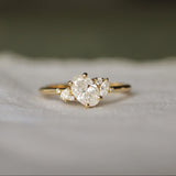 Gold engagement ring with oval, pear and marquise diamonds on a soft fabric background