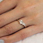 close up of hand wearing a yellow gold and diamond cluster engagement ring