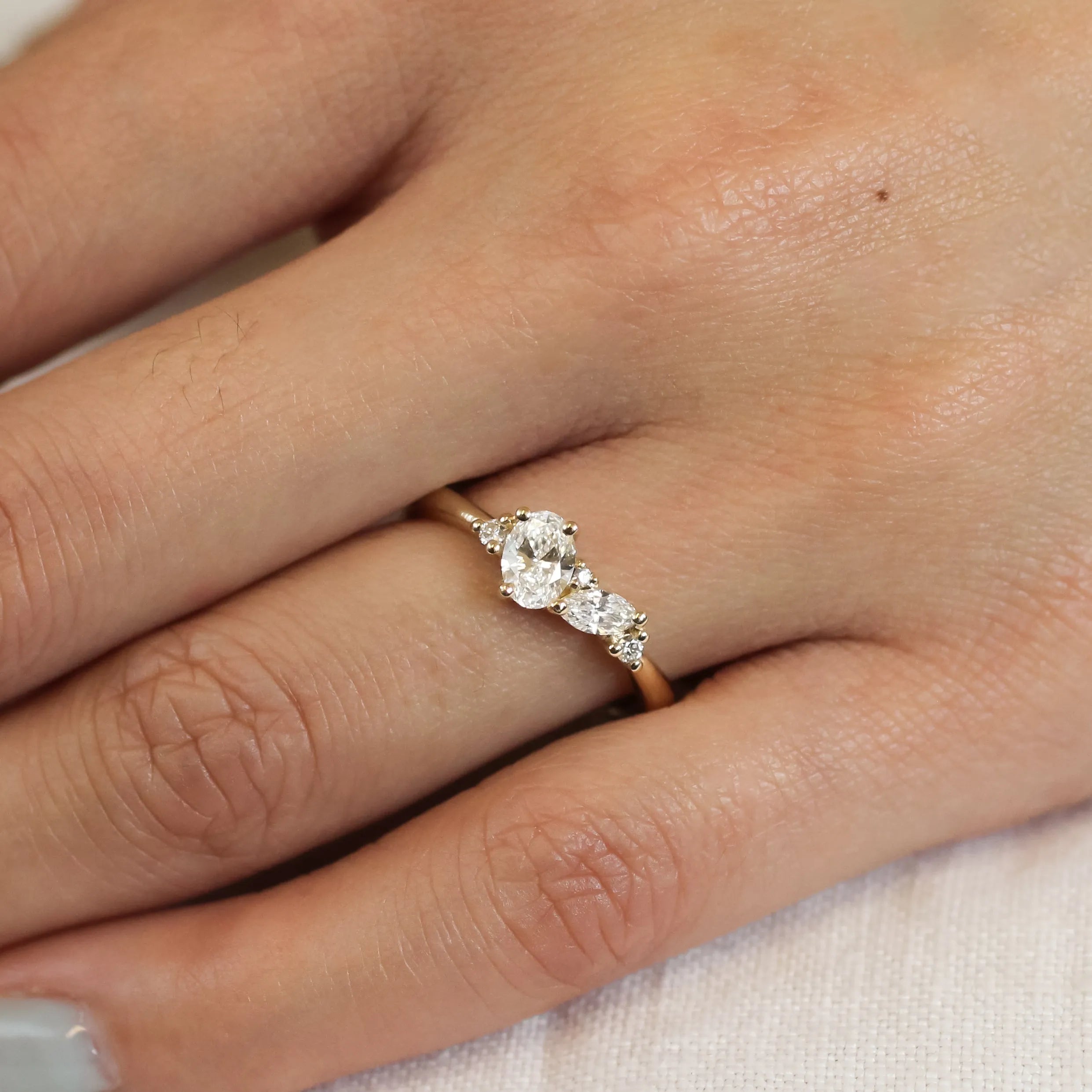 close up of hand wearing a yellow gold and diamond cluster engagement ring