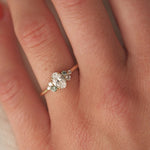 Close-up of a hand wearing a diamond ring with small green sapphires with a soft focus background