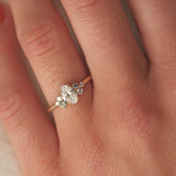 Close-up of a hand wearing a diamond ring with small green sapphires with a soft focus background