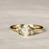 Gold ring with diamonds and green sapphires on a textured beige surface