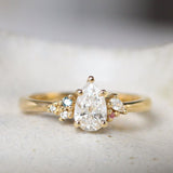 Gold ring with a pear-shaped diamond and small blue and pink sapphires on a textured surface