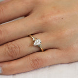 close up of hand wearing a yellow gold engagement ring with pear shaped diamond and pink and blue sapphires